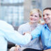 Smiling young couple shaking hands with their property consultant